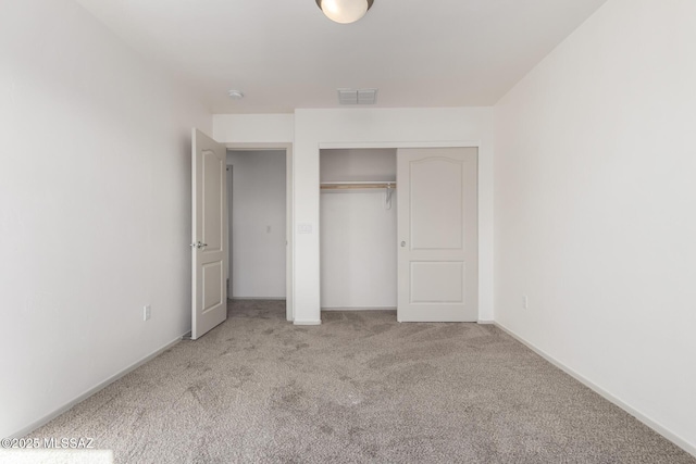 unfurnished bedroom with a closet, light colored carpet, visible vents, and baseboards