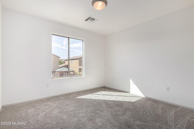 empty room featuring carpet floors, visible vents, and baseboards