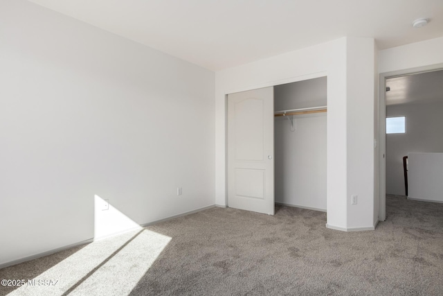 unfurnished bedroom featuring carpet floors, a closet, and baseboards