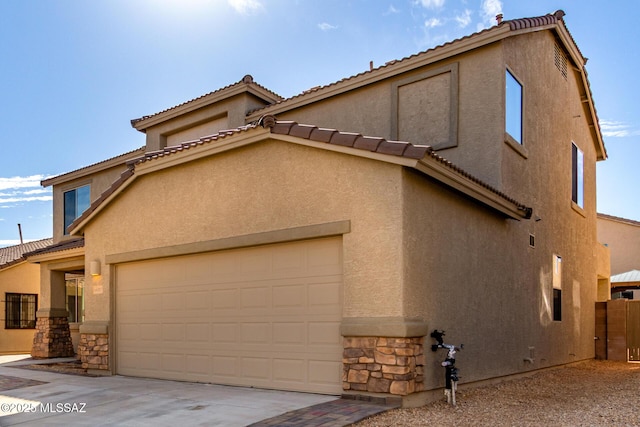 view of front of property with a garage, stone siding, concrete driveway, and stucco siding