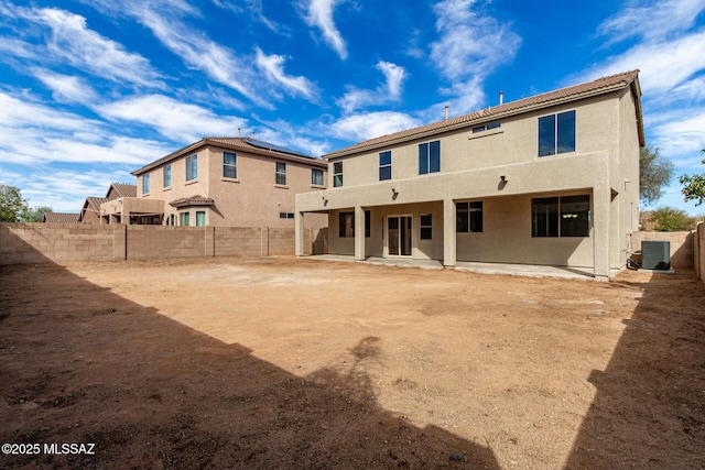 rear view of house featuring stucco siding, a fenced backyard, central AC unit, and a patio