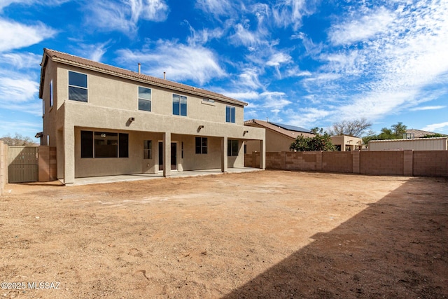 rear view of property with a fenced backyard, a patio, and stucco siding