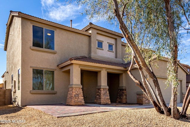 view of front of house featuring stone siding, fence, and stucco siding