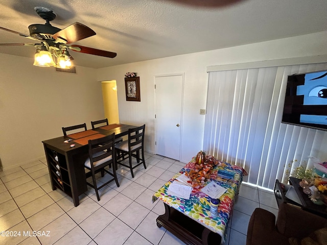 dining space with a textured ceiling, light tile patterned floors, and ceiling fan