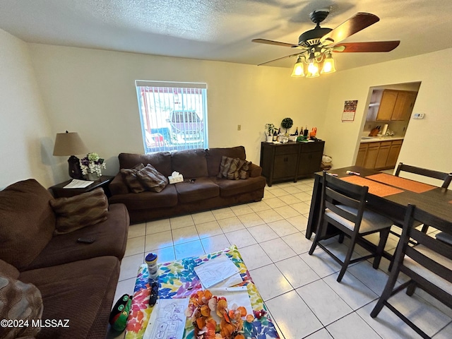 living room with ceiling fan, a textured ceiling, and light tile patterned floors