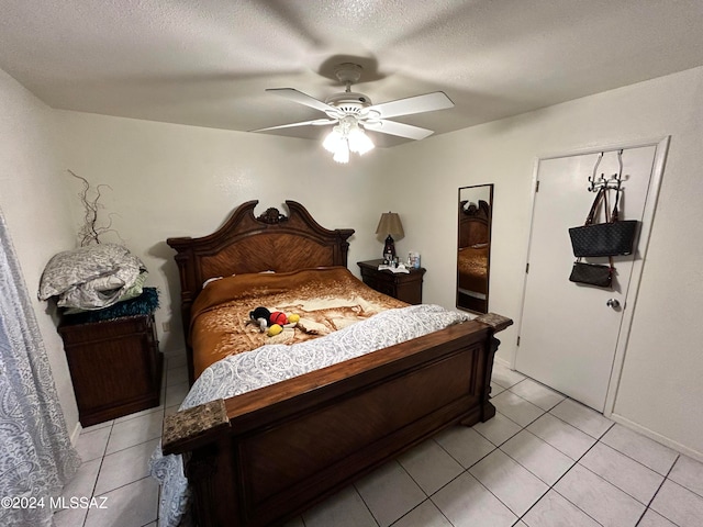 bedroom with a textured ceiling, light tile patterned flooring, and ceiling fan