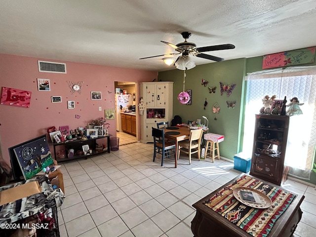 living room featuring a textured ceiling, light tile patterned floors, and ceiling fan