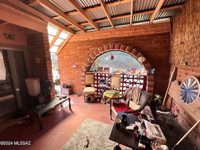 unfurnished living room with concrete floors, brick wall, and vaulted ceiling