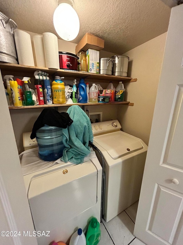 washroom with a textured ceiling, washing machine and dryer, and light tile patterned floors