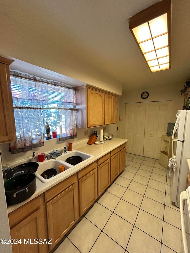 kitchen with sink, light tile patterned flooring, and white refrigerator