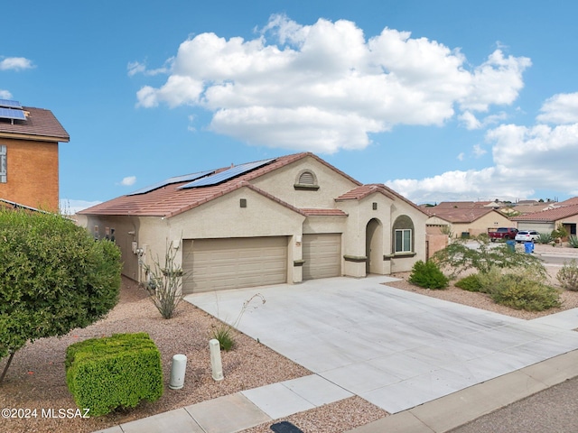 mediterranean / spanish house featuring a garage and solar panels