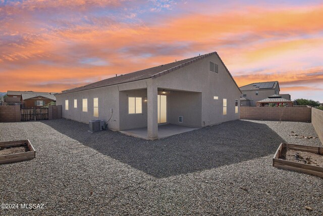 back house at dusk with central AC and a patio