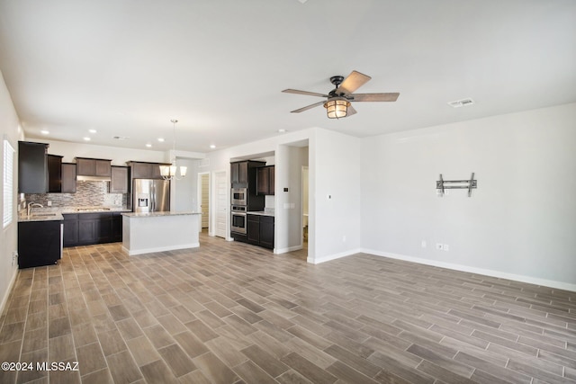 unfurnished living room with ceiling fan with notable chandelier, light wood-type flooring, and sink