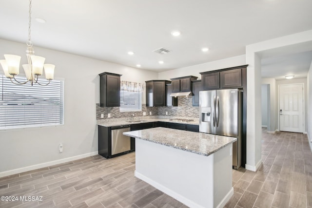 kitchen featuring light hardwood / wood-style floors, a kitchen island, sink, appliances with stainless steel finishes, and a wealth of natural light