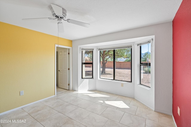 empty room featuring ceiling fan, a textured ceiling, and light tile patterned floors