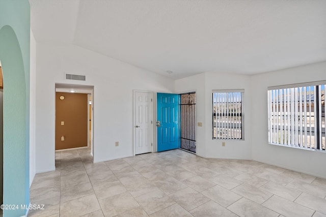 tiled empty room featuring vaulted ceiling