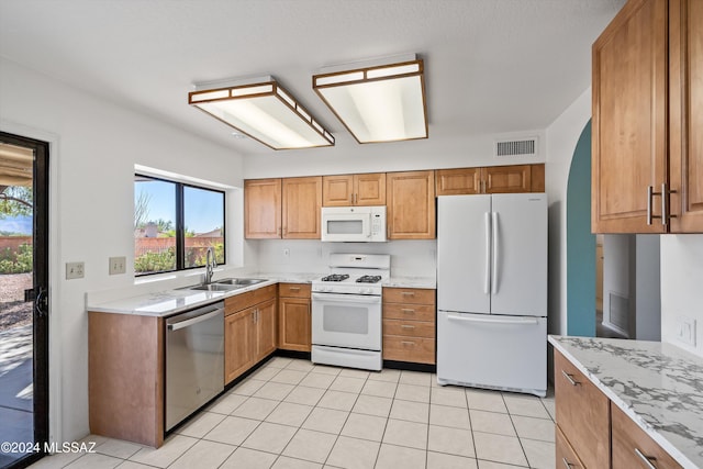 kitchen featuring sink, light stone counters, white appliances, and light tile patterned floors