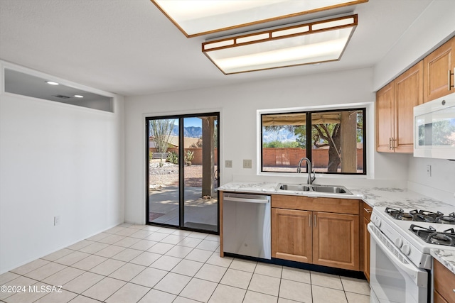 kitchen featuring sink, light tile patterned flooring, white appliances, and plenty of natural light