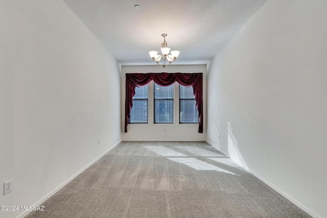 carpeted empty room with a notable chandelier