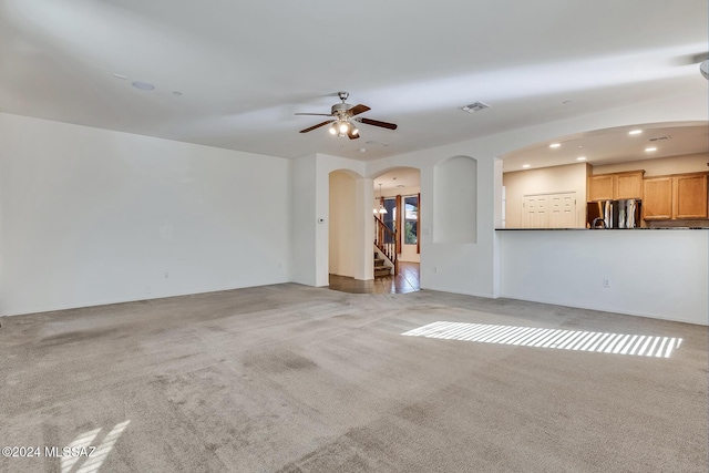 unfurnished living room featuring light carpet and ceiling fan