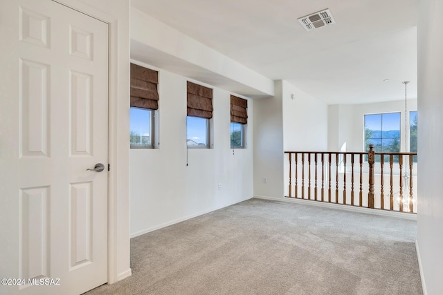 empty room featuring plenty of natural light and light colored carpet