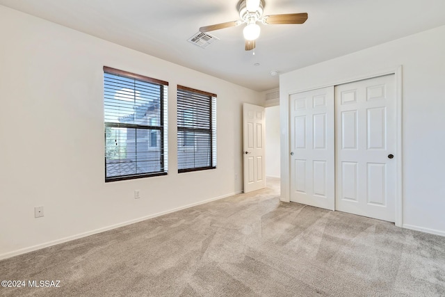 unfurnished bedroom with light colored carpet, a closet, and ceiling fan