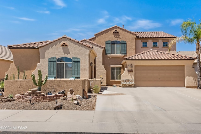mediterranean / spanish-style house with stucco siding, driveway, a tile roof, and a garage