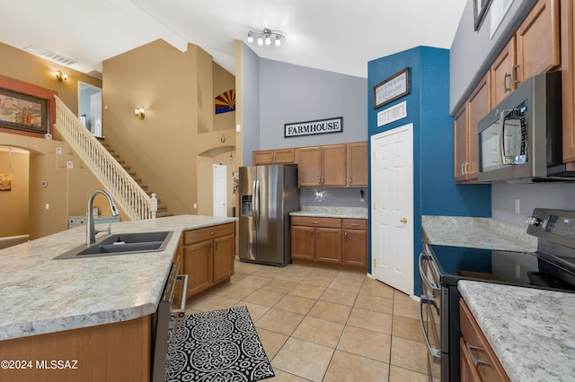 kitchen with sink, light tile patterned floors, stainless steel appliances, high vaulted ceiling, and an island with sink