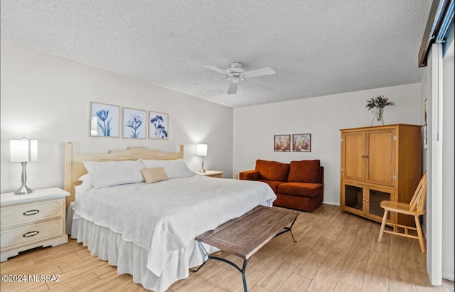 bedroom featuring light hardwood / wood-style flooring, a textured ceiling, and ceiling fan