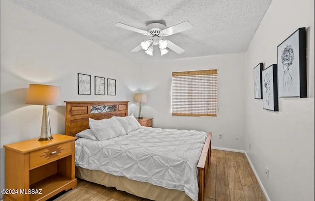 bedroom featuring ceiling fan, hardwood / wood-style floors, and a textured ceiling