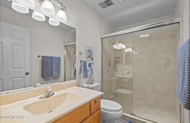 bathroom featuring a shower with shower door, vanity, and toilet