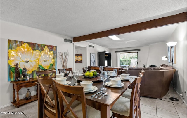 dining area featuring light tile patterned flooring, beamed ceiling, and a textured ceiling