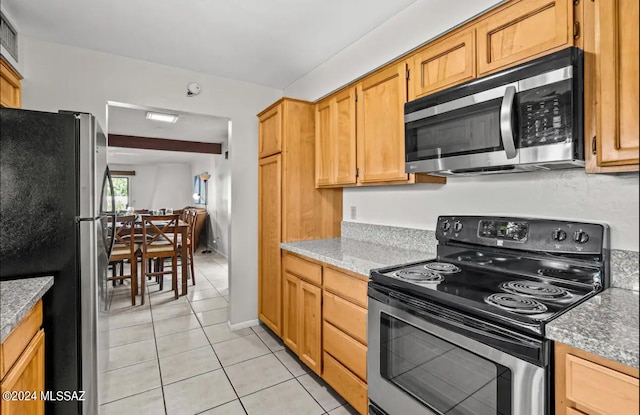 kitchen featuring light tile patterned floors, light stone countertops, and stainless steel appliances