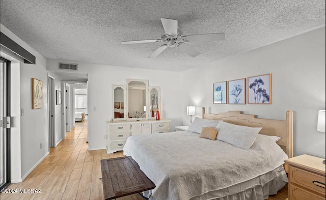 bedroom with ceiling fan, a textured ceiling, and light wood-type flooring