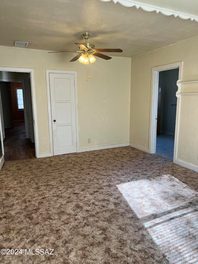 unfurnished room featuring ceiling fan, a textured ceiling, and dark colored carpet