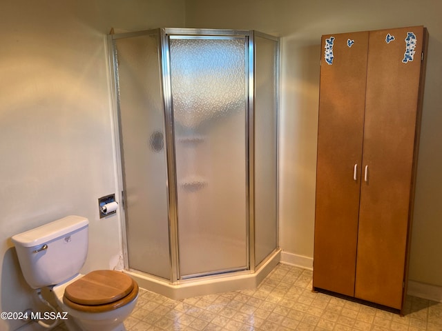 bathroom featuring toilet and a shower with shower door