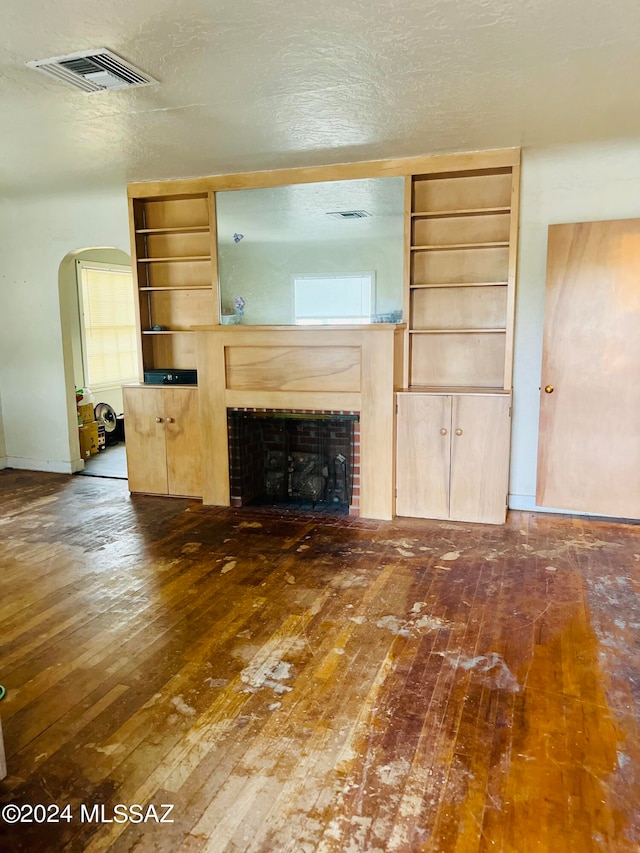 unfurnished living room with a textured ceiling and dark wood-type flooring