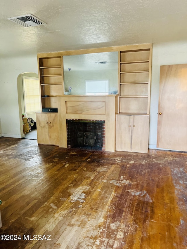 172 S Austin Blvd, Willcox, AZ 85643 - unfurnished living room featuring arched walkways, visible vents, a fireplace, and dark wood-style flooring