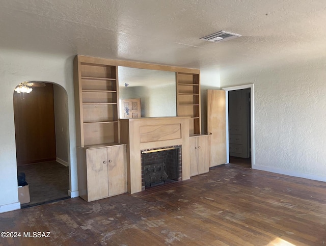 unfurnished living room with dark wood-type flooring, ceiling fan, and a textured ceiling