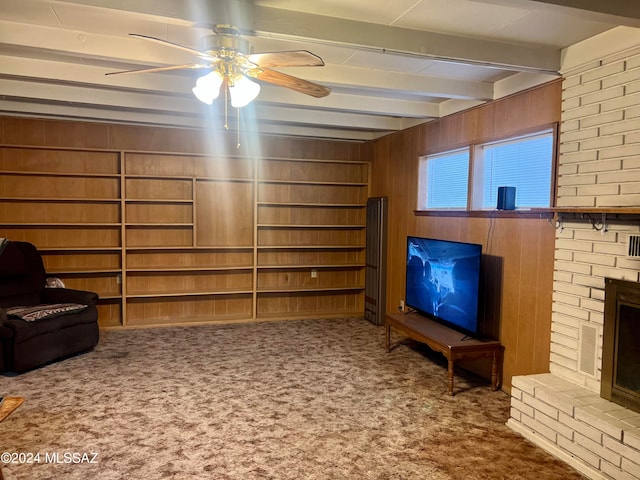 unfurnished room featuring a fireplace, carpet floors, ceiling fan, wooden walls, and beam ceiling