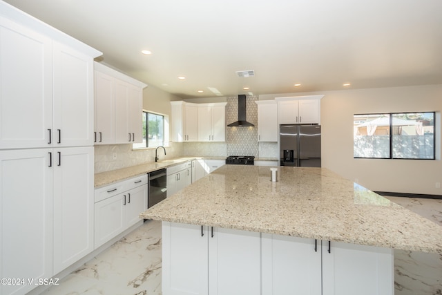 kitchen featuring stainless steel fridge, a kitchen island, wall chimney exhaust hood, and white cabinetry