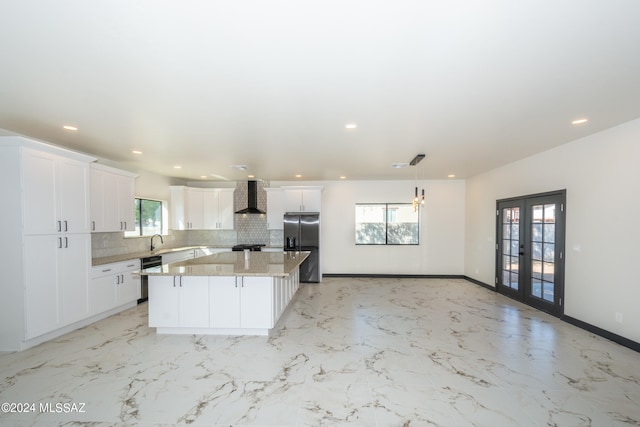 kitchen with a center island, french doors, tasteful backsplash, wall chimney range hood, and stainless steel fridge with ice dispenser
