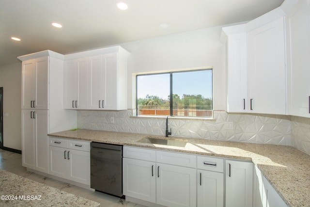 kitchen featuring light stone counters, tasteful backsplash, sink, black dishwasher, and white cabinetry