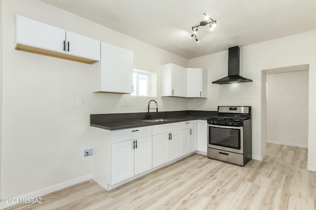 kitchen with stainless steel range with gas stovetop, wall chimney range hood, white cabinetry, and sink