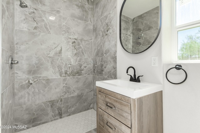 bathroom featuring tiled shower and vanity