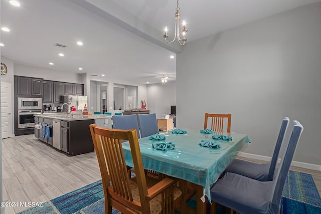 dining area featuring light hardwood / wood-style floors, sink, and ceiling fan with notable chandelier