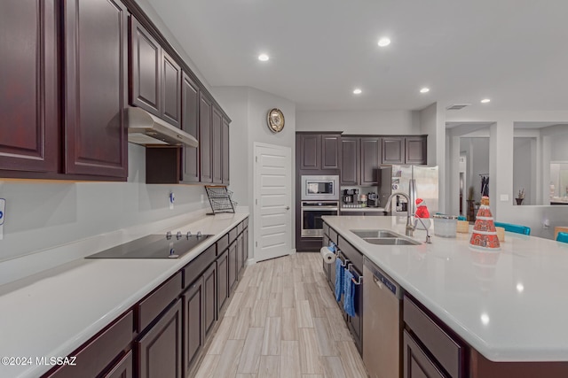 kitchen featuring an island with sink, dark brown cabinets, stainless steel appliances, sink, and light hardwood / wood-style floors