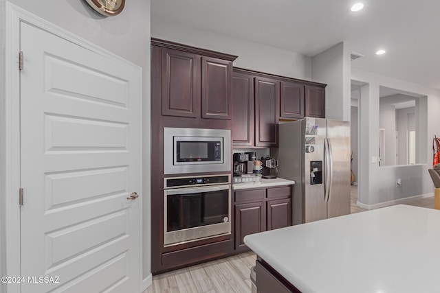 kitchen with appliances with stainless steel finishes, light hardwood / wood-style flooring, and dark brown cabinets