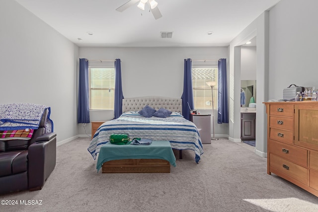 bedroom with ensuite bath, light carpet, and ceiling fan