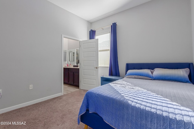 bedroom featuring ensuite bathroom and light carpet